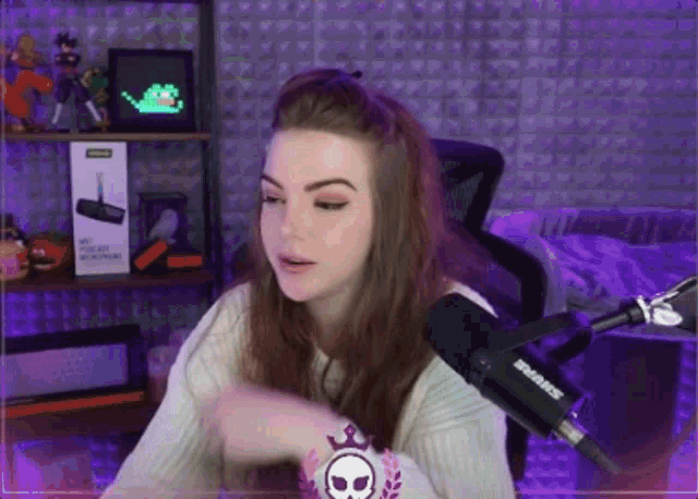 a woman sitting in front of a shure microphone in a purple room