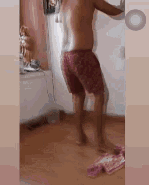 a shirtless man in pink shorts is standing in a room .