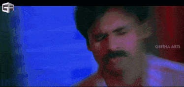 a man with a mustache is talking to another man in a dark room .
