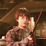 a young boy wearing glasses is holding a wand in his hands