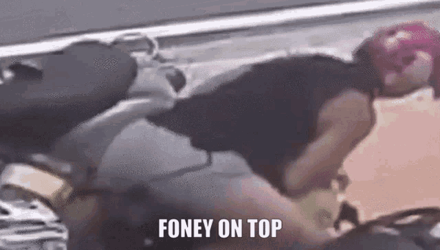 a person is laying on top of a motorcycle with the words `` foney on top '' written on the bottom .