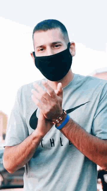 a man wearing a face mask and a nike t-shirt clapping his hands