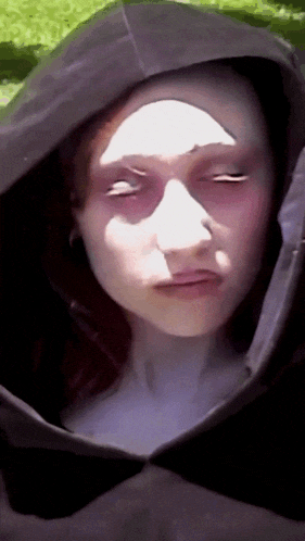 a close up of a person 's face with white eyes and a hood