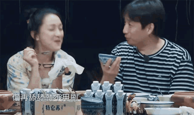 a man and a woman are sitting at a table with bowls and a sign that says ' a ' on it