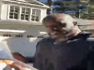 a man with a beard is holding a piece of paper in front of a house .