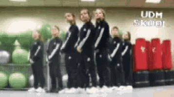 a group of girls are standing in a gym with the words udm skool on the wall