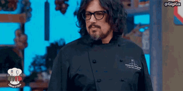a man with glasses and a beard is wearing a chef 's jacket