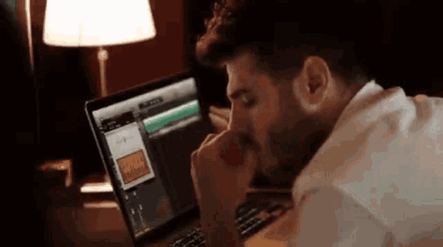 a man is sitting in front of a laptop with a screen that says ' a ' on it