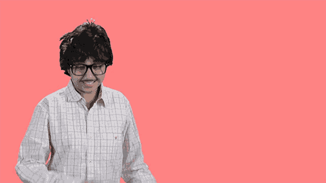 a man wearing glasses stands in front of a pink background with cheers written on it