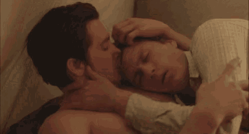a man and a woman are kissing while laying in bed .