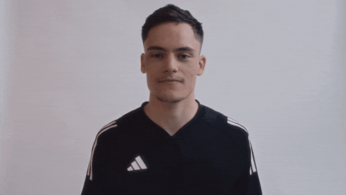 a man wearing a black adidas shirt with white stripes