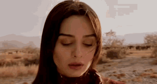 a close up of a woman 's face with her eyes closed in the desert