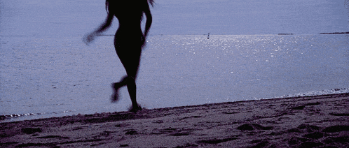 a woman in a bikini is running on a beach
