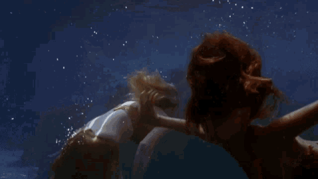 a mermaid with red hair is swimming in the water