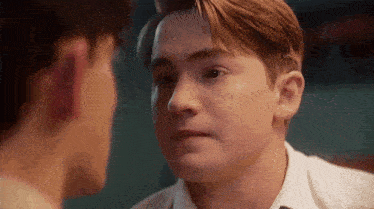 a man is looking at another man 's face and making a funny face .