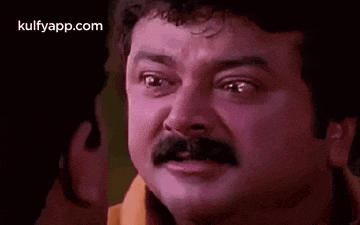 a man with a mustache is making a funny face while talking to another man .