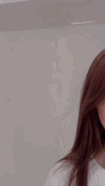 a woman with long brown hair is wearing a white shirt and making a funny face .