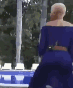 a woman in a blue dress is standing next to a pool .