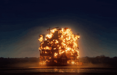 a large building is on fire at night with a blue sky behind it