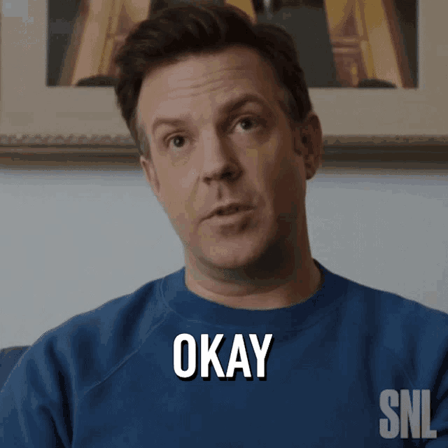 a man wearing a blue sweater that says okay on it