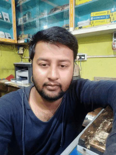 a man taking a selfie in front of a shelf that has a box on it that says ' samsung '