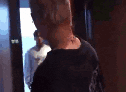 a man with a tattoo on his neck is standing in a doorway