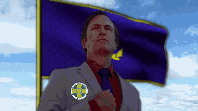 a man in a suit and tie stands in front of a flag with a badge on his jacket that says united states of america