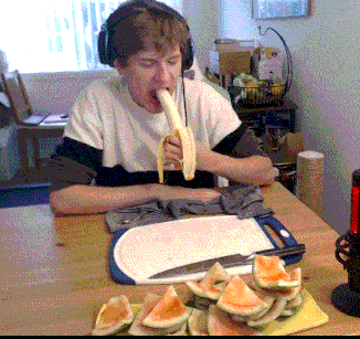 a young man wearing headphones eating a banana