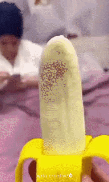 a person is holding a banana that has the word xpto creative on the bottom