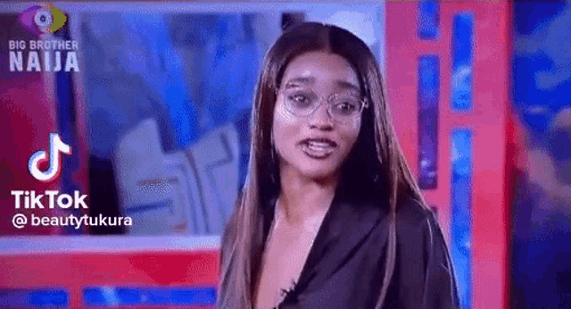a woman wearing glasses and a black shirt is standing in front of a red and blue background .