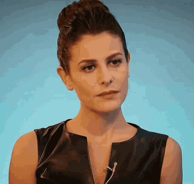 a woman wearing a black leather dress has a microphone in her neck