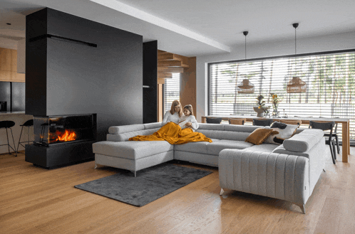two women sit on a couch in a living room with a fireplace