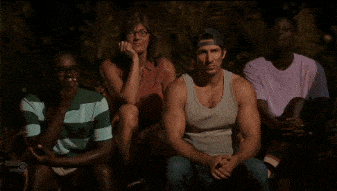 a man in a tank top and hat is standing next to another man in a pink shirt .