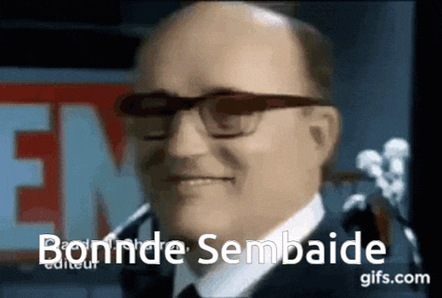 a bald man wearing glasses and a suit says bonnde sembaide