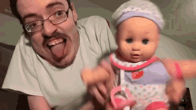 a man with glasses is sticking his tongue out while holding a doll