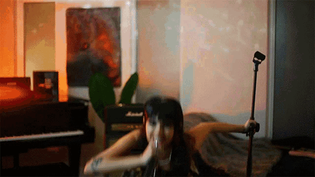 a woman singing into a microphone in front of a marshall piano