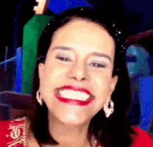 a woman wearing red lipstick and earrings is smiling