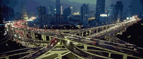 a busy intersection with a city in the background at night