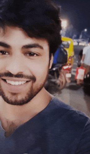 a man with a beard wearing a blue shirt smiles