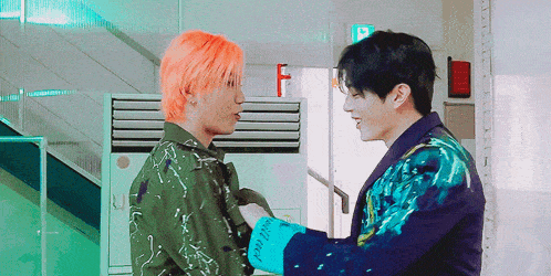 two men are standing next to each other and one has orange hair