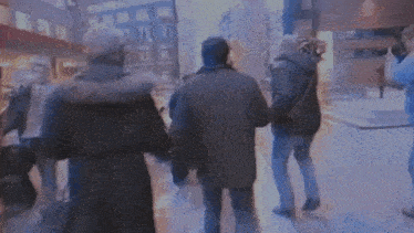 two men are fighting on a street with a car in the background