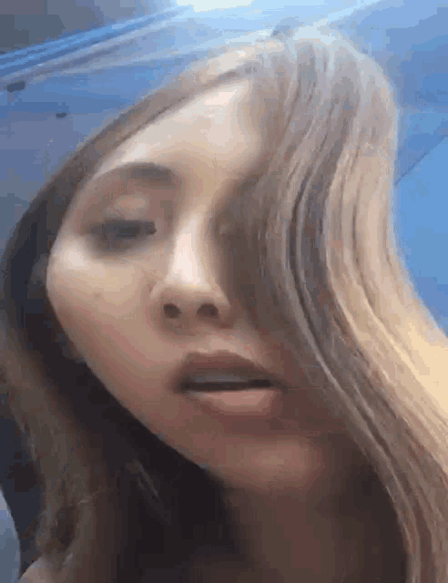a close up of a woman 's face with long hair and a blue background