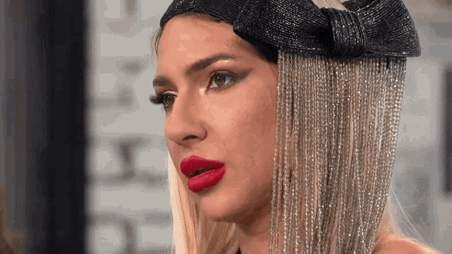 a close up of a woman 's face with red lipstick and a black hat