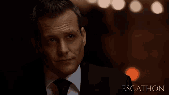 a close up of a man in a suit and tie with the words escathon behind him