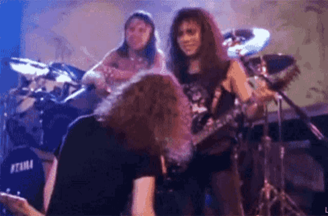 a group of people are playing instruments on a stage and one of them is kneeling down .