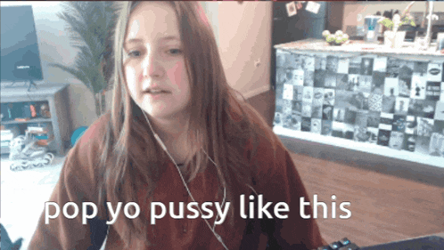 a girl wearing headphones says pop yo pussy like this in front of a kitchen counter