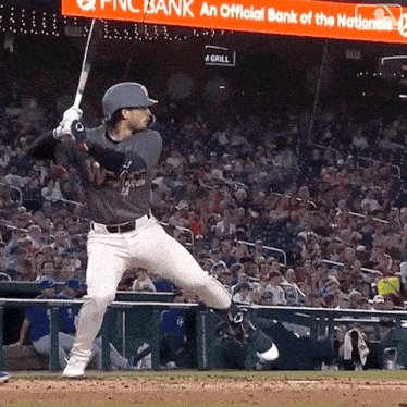 a baseball player swings his bat in front of a sign that says pnc bank an official bank of the nationals