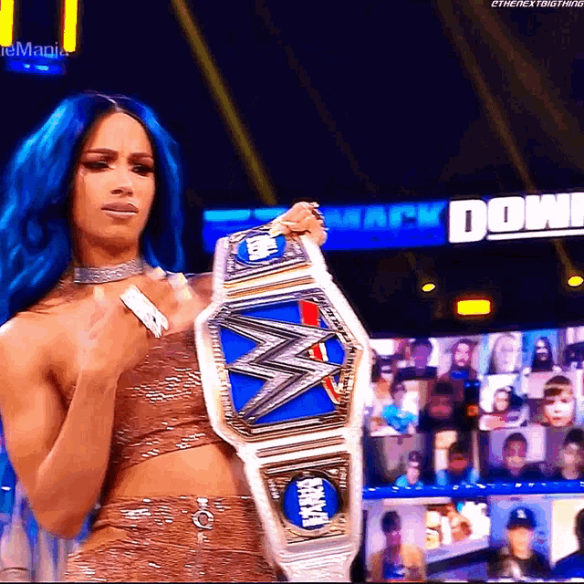 a woman with blue hair is holding a wrestling belt