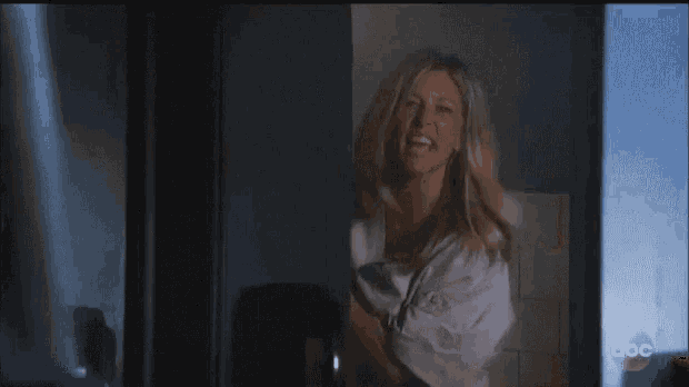 a woman is standing in front of a window in a dark room .