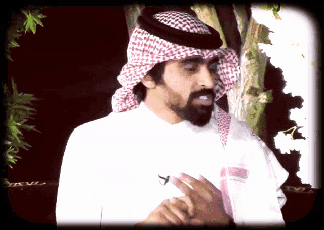 a man with a beard wearing a white shirt and a head scarf